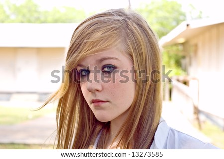 stock photo Pretty blond teen girl by a school stares into the camera in 