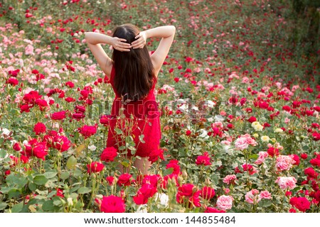 A beautiful woman with long hair plays in the rose garden