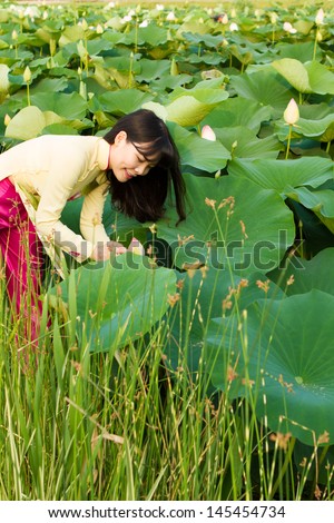 Beautiful girl in tradition dress plays in the lotus garden