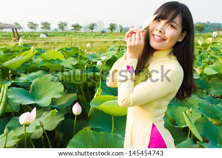 Beautiful girl in tradition dress plays in the lotus garden
