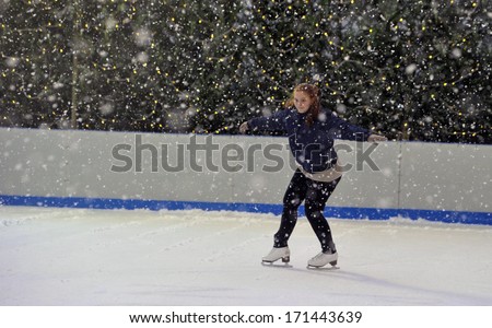 MILAN, ITALY - FEBRUARY 07: a girl ice skating in an outdoor public ice skating ring under a snowfall in Milan. February 07, 2009.