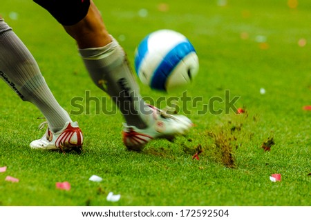 MILAN, ITALY - SEPTEMBER 29: Italian professional Serie A soccer match in Milan September 29, 2006. A football player close up kicking the ball with the green pitch on the background.