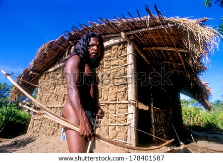 Kandy, Sri Lanka-June 07, 2007: Jungle Man Posing With His Arch In Front Of His Thatched Hut.