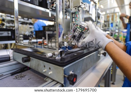 MEDOLLA, ITALY-OCTOBER 17, 2012: Hands with gloves assembling a medical device on a factory line, at the Gambro factory, Italian division.