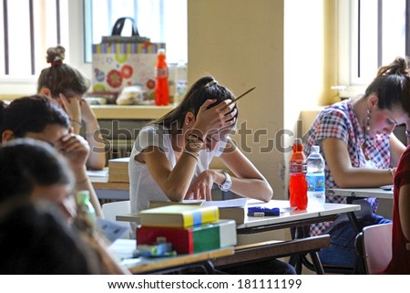 MILAN, ITALY-JUNE 20, 2012: College students seat on school desk in the exam room, for the secondary school\'s final exams, at the Artemisia Gentileschi School in Milan.
