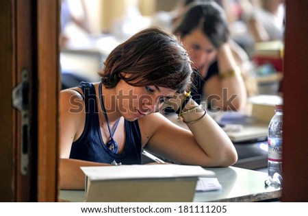 MILAN, ITALY-JUNE 20, 2012: College students seat on school desk in the exam room, for the secondary school's final exams, at the Artemisia Gentileschi School in Milan.