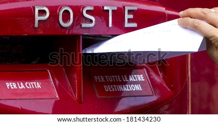 MILAN, ITALY-FEBRUARY 22, 2012: Hand sending a letter in a red mail box outside a post office in Milan.