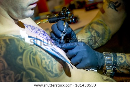 MILAN, ITALY-FEBRUARY, 12, 2012: Professional tattooer drawing a tattoo on a man chest, during an International Tattoo event in Milan.