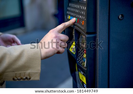 MILAN, ITALY-JANUARY 24, 2012: Man\'s finger digit on a parking payment machine on the street, in downtown Milan.