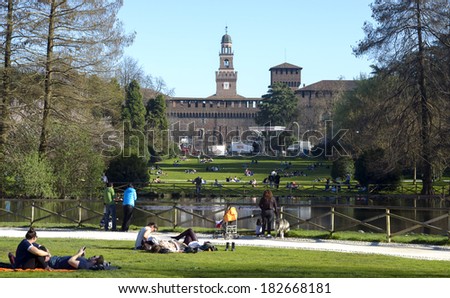 MILAN, ITALY-MARCH 17, 2014: people laying on the grass, at Sempione Park, for the beginning of springtime,  with the Castello Sforzesco in the background, downtown Milan.