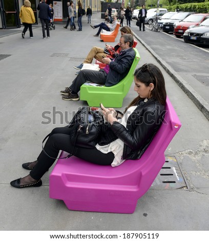 MILAN, ITALY-APRIL 08, 2014: People seating outdoor on a design plastic chairs at the Fuorisalone, during the International Design Fair, Salone del Mobile, in Milan.
