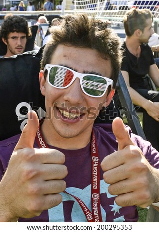 MILAN, ITALY-JUNE 20, 2014: italian soccer fan with italian sun glasses on the Naviglio Grande canal, watching the Brazil 2014 World Cup football match Italy vs Costa Rica, in Milan.