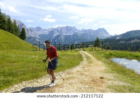 CORVARA, ITALY-AUGUST 06, 2014: man walking on a Dolomites mountains path surrounded rocky mountains, in Corvara.