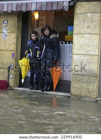 MILAN, ITALY-NOVEMBER 26, 2002: woman and child waiting to cross a flooded road during a flood caused by heavy rain, in Milan.