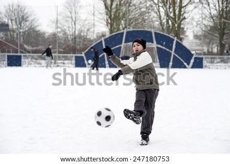 MALMO, SWEDEN-FEBRUARY 20, 2008: children playing soccer in a playground covered by snow, in Malmo.