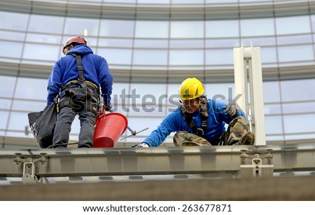 MILAN, ITALY-MARCH 23, 2015: skyscraper workers wearing safety helmet and security ropes, while cleaning windows glasses of the Unicredit tower, in Milan.