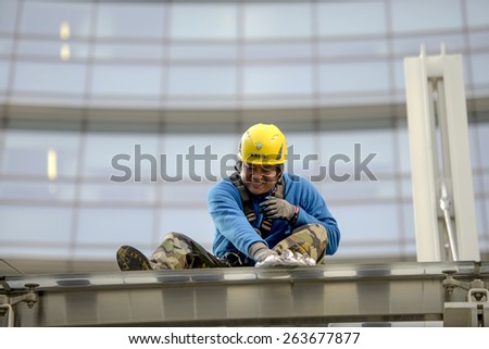 MILAN, ITALY-MARCH 23, 2015: skyscraper workers wearing safety helmet and security ropes, while cleaning windows glasses of the Unicredit tower, in Milan.