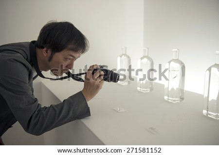 MILAN, ITALY-APRIL 17, 2015: visitor takes picture of rain bottle, art design exposition of japanese brand Nendo, during the design week, in Milan.