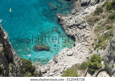 CAPRI, ITALY-JUNE 26, 2015: top view of the island rocky coast line with a few swimmers on the beautiful emerald sea, in Capri.