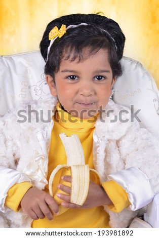 Little girl eating banana sitting on a feeding chair