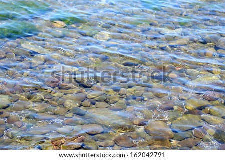 Shiny stones under the water. Marine shallow water. Stones underwater.