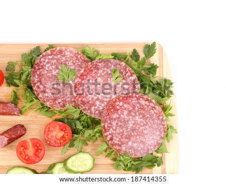 Sausage salami and vegetables on wooden platter. Whole background.