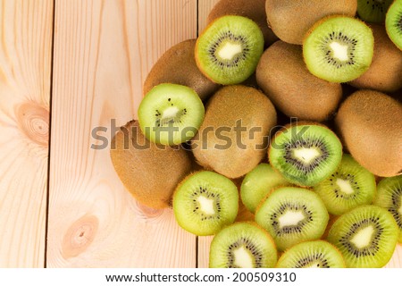 Kiwi in two halves with other kiwis on the back. Wooden background.
