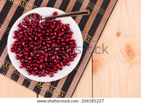 red grains of a pomegranate on the wooden background