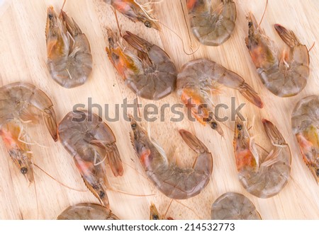 Raw shrimps on wooden platter. Whole background.