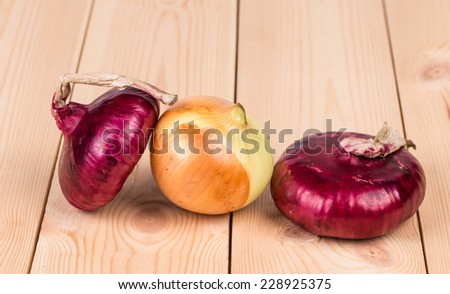 Red and white onions on wooden platter. Whole background.
