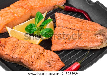 Fried salmon fillet in pan with lemon. Whole background.