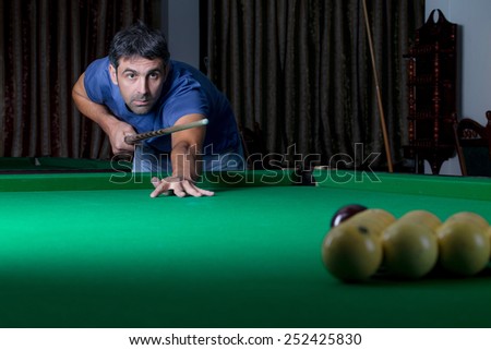 young man lines up his shot as he breaks the balls for the start of a game of billiards