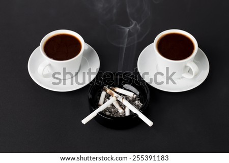 White cups of coffee with ashtray and cigarettes on the black background