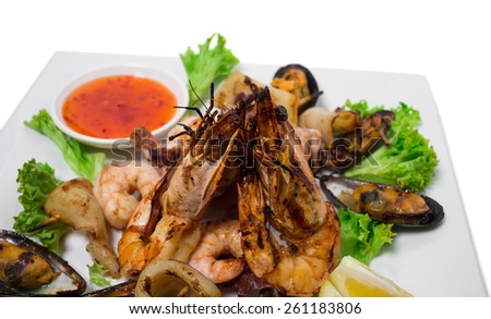 Delicious grilled seafood platter with hot sauce. Isolated on a white background.