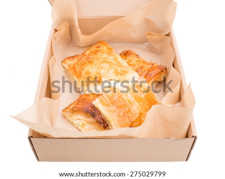 Heat puff cakes filled with a soft cheese in cardboard box. Isolated on a white background.