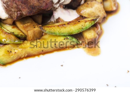 Grilled beef steak covered with delicious sauce and zucchini with champignons as a garnish. Macro. Photo can be used as a whole background.