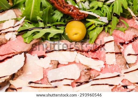 Delicious roast beef with arugula and parmesan covered with balsamic vinegar. Macro. Photo can be used as a whole background.