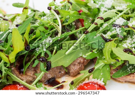 Warm beef shish kebab with fresh arugula and grated parmesan cheese covered with balsamic vinegar. Macro. Photo can be used as a whole background.