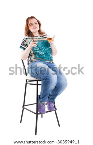 Smiling redhead plus size wreckled model sitting on the bar chair with glass of whiskey and cigar. Studio shot. Isolated on a white background.