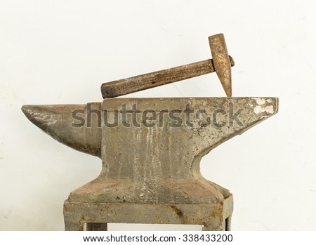 Old hammer and anvil tools against white clay wall as a background.