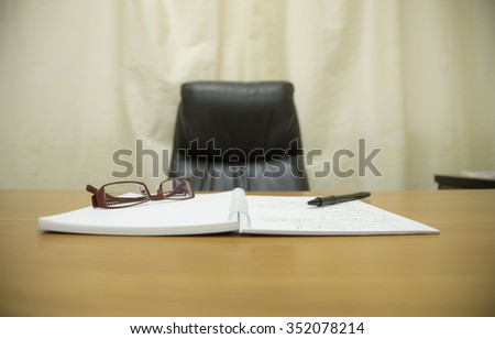 Office chair and desk of boss with notebook and pen and glasses create a comfortable workplace