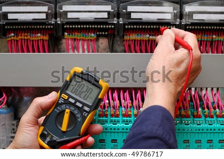 Technician testing a control panel wiht measurement instrument, close-up