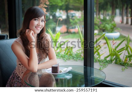 Portrait of young pretty smiling woman with cake at coffee shop
