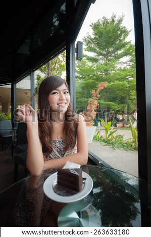 Portrait of young pretty smiling woman with cake at coffee shop