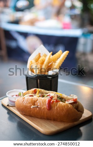 Beef Hotdog with french fries on wooden plate in restaurant