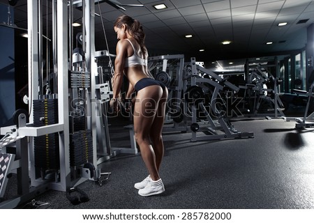 Nice sexy woman doing triceps workout in gym