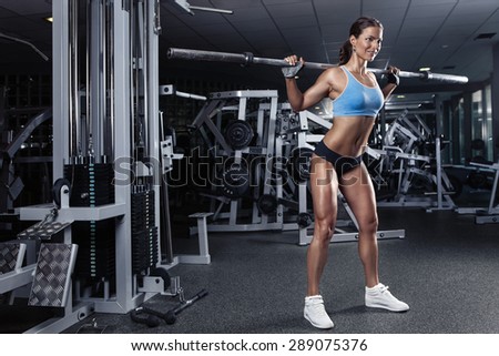 beautiful sporty sexy woman doing squat workout in gym