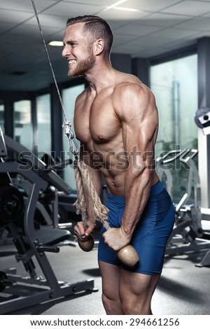 Muscular bodybuilder guy doing triceps exercises in gym
