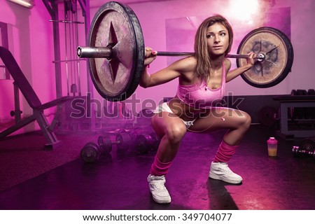 beautiful sporty sexy woman doing squat workout in gym