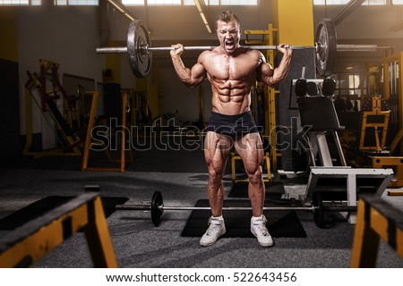 Muscular bodybuilder guy doing exercises with dumbbell in yellow gym